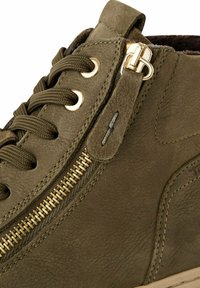 Baskets montantes en cuir vert olive avec accent de fermeture éclair doré, lacets ronds et surface texturée, présentant des détails de couture sur les côtés.