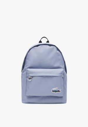 Zaino viola chiaro con tasca frontale con zip, manico nero e piccola toppa con logo coccodrillo sulla parte inferiore destra della tasca.