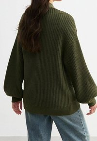 Vihreä neulepaita, jossa on väljä istuvuus, pallohihat ja resorireuna. Valmistettu teksturoidusta kankaasta lisälämmön ja mukavuuden takaamiseksi.