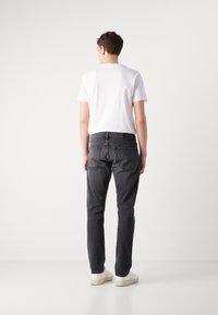 Sive kavbojke s slim fit krojem in zadnjimi žepi, v kombinaciji s preprosto belo majico s kratkimi rokavi in belimi supergami. Preprost in sproščen slog.