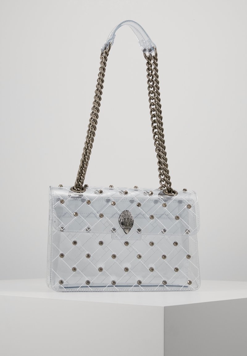 Borsa a mano di plastica trasparente con design trapuntato, borchie dorate e chiusura metallica. Presenta un manico trasparente e una tracolla intrecciata.