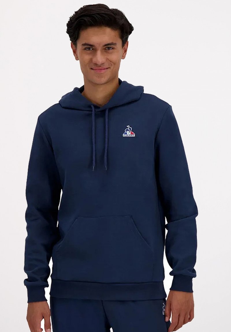 Felpa con cappuccio blu navy realizzata in morbido tessuto, con tasca anteriore e un piccolo logo sul petto. Vestibilità classica con polsini a costine.