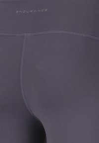 Marinblå stretchleggings med en slät yta, med platta sömmar och varumärket "ENDURANCE" präglat nära midjan.