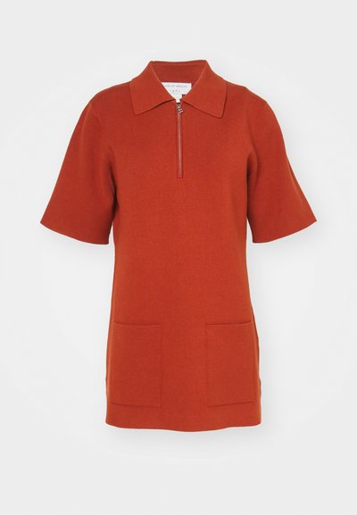 Robe tricot rouge à manches courtes, à col, et avec une fermeture éclair à l'avant. Présente deux détails de poches avant. Texture lisse.