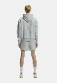 Light gray hoodie with a large back graphic, accompanied by matching shorts. Both garments feature a soft texture and relaxed fit.