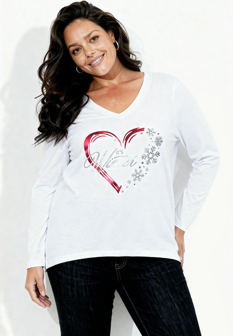 Biała koszulka z długim rękawem i dekoltem w serek, z czerwonym sercem i napisem "To jest zima", ozdobiona srebrnymi płatkami śniegu.