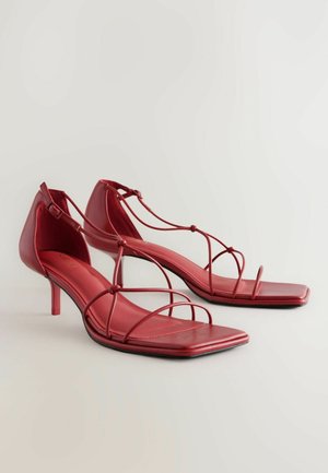 Punane nahast kõrge kontsaga sandaalid ruudukujuliste varvastega, mitme õhukese rihmaga jala üle ja reguleeritava pahkluu pannaliga. Tekstuuriga sisetald.