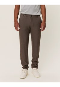 Brune rutete bukser med skreddersydd passform, med knappelukking, beltehemper og sidelommer, kombinert med hvite sneakers.