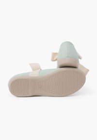 Chaussures en tissu vert menthe avec une semelle rembourrée, forme arrondie et sangle beige. La semelle texturée présente des rainures pour une meilleure adhérence.