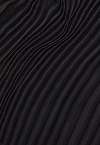 Tissu noir plissé avec une texture lisse et ondulée, comportant des plis verticaux, créant un élément de design rythmique à travers le matériau.