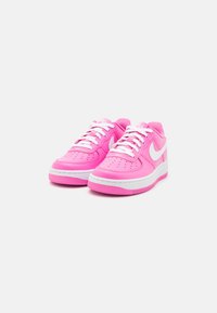 Vaaleanpunaiset Nike Air Force 1 -tennarit, joissa on sileä nahkapinta, valkoiset yksityiskohdat, rei'itetty varvasosa ja kumipohja. Valkoiset nauhat ja brändäysyksityiskohta.