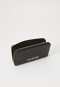 Črn usnjen denarnica z zadrgo, ki ima strukturirano površino in zlat logo "LOVE MOSCHINO" spredaj.