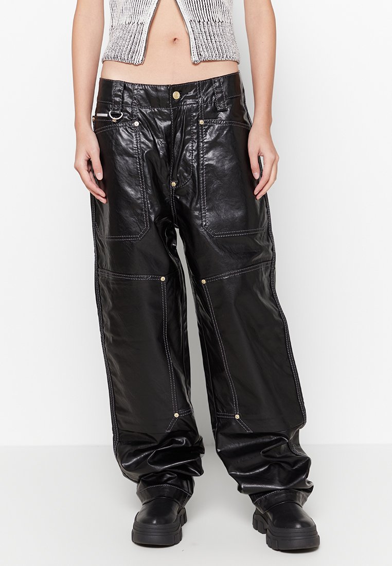 Schwarze Leder-Hosen mit weitem Bein, verziert mit goldfarbenen Hardware-Details, kontrastierenden weißen Nähten und einem hoch taillierten Design. Glatte, glänzende Textur.