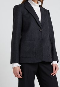 Blazer grigio carbone realizzato in un tessuto testurizzato, dotato di chiusura con un bottone singolo, due grandi tasche frontali e revers a punta.