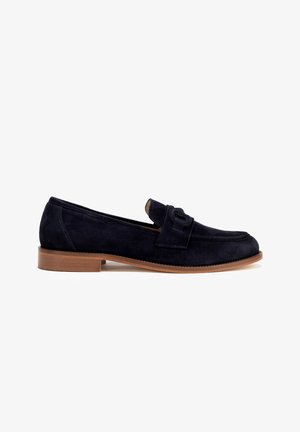 Mocassini in suede blu navy con sole piatta marrone, caratterizzati da un accento legato sulla parte anteriore e un design della punta arrotondato.