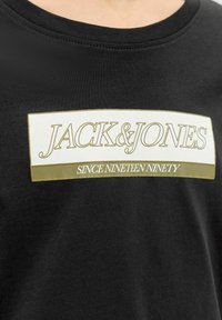 Zwarte katoenen T-shirt met een rechthoekige grafiek met 'JACK & JONES' in wit en goud, en de tekst 'SINCE NINETEEN NINETY' eronder.