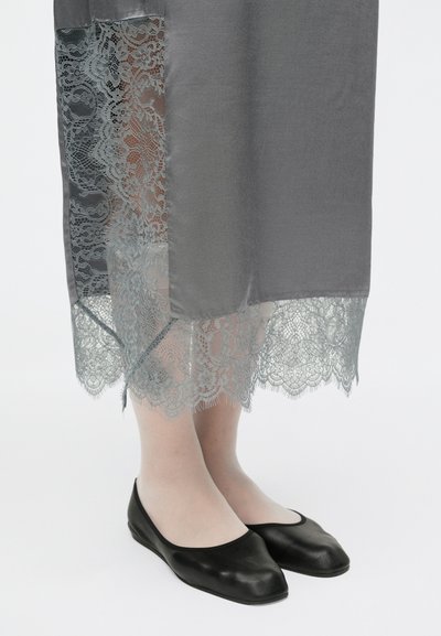 Rochie gri cu tiv din dantelă, suprapusă peste un material deschis la culoare. Pantofi negri cu talpă joasă vizibili sub rochie. Textură netedă și lucioasă.