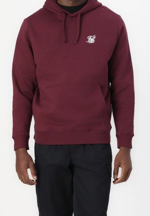 Burgundy hoodie made of soft fabric, featuring a front pocket and drawstring hood. Includes a small white logo on the chest.