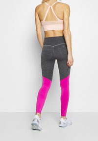 Träningskläder med en rosa nät-bh och grå leggings med rosa detaljer. Byxorna har en slät textur och en åtsittande design.