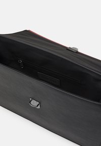 Sort syntetisk taske med et lynlås hovedrum. Har en lille intern lynlås lomme og et sølvfarvet hardware-øjeblik på forsiden.