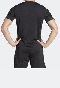 Svart sportströja med korta ärmar, rund hals och kontrasterande sömmar. Bärs tillsammans med svarta shorts som framhäver en figurnära design.