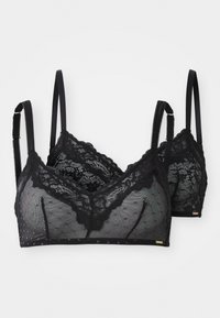 Deux bralettes en dentelle noire avec des bretelles réglables et de délicats motifs floraux, présentées sur un fond blanc.