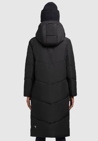 Schwarze Pufferjacke mit Kapuze, die ein Zickzackmuster und Seitenschlitze aufweist. Der Stoff ist glatt und isoliert für Wärme.
