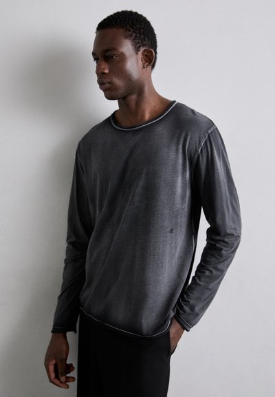 T-shirt de manga longa cinza com decote redondo e costuras contrastantes. Textura suave com minimalismo na marca no lado inferior.