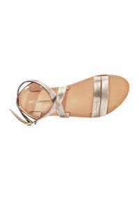 Metallieke gouden sandalen met kruislingse straps, een platte zool en een beige leren binnenzool. Voorzien van een gesp-sluiting op de enkelband.
