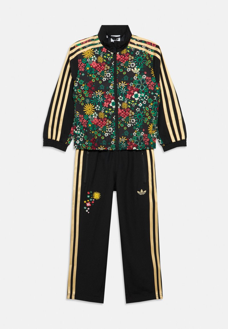 Μαύρο σετ φόρμας με μπουφάν διακοσμημένο με ανθικό μοτίβο και χρυσές ρίγες, συνοδευόμενο από παντελόνι με το ίδιο σχέδιο. Το μπουφάν έχει φερμουάρ μπροστά και ελαστικές μανσέτες.