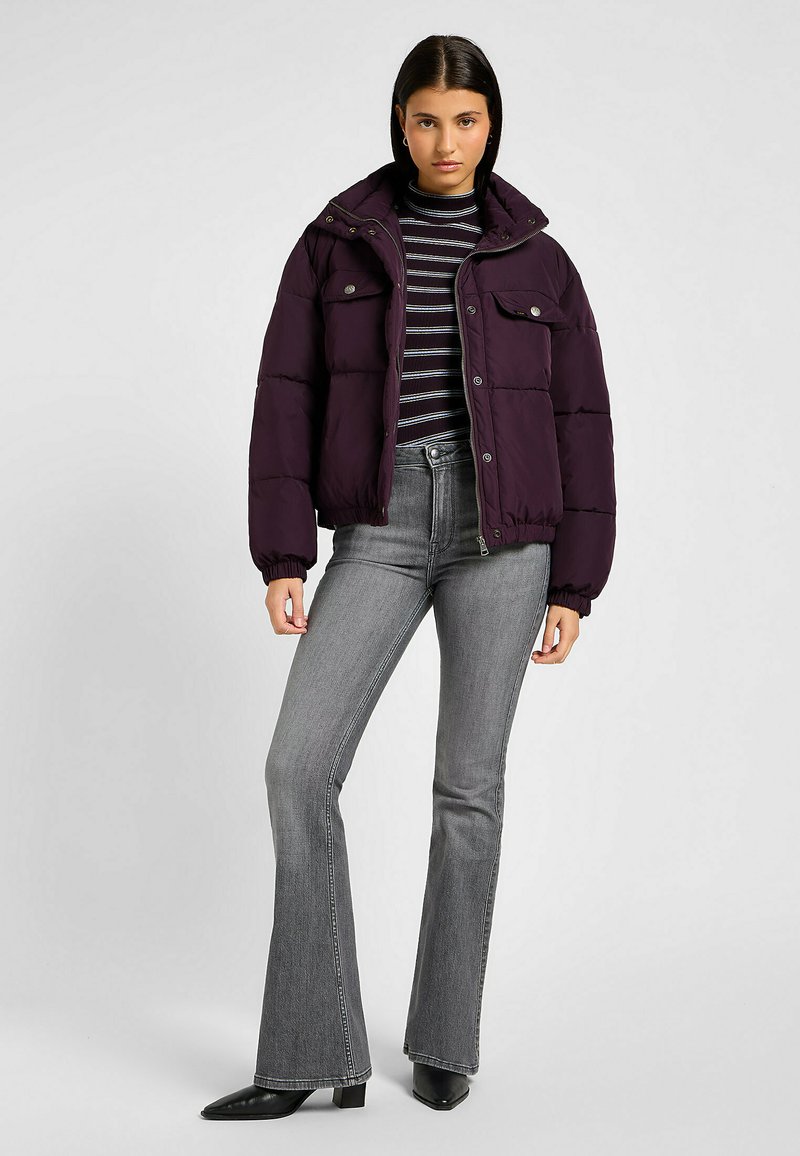 Pufferjack in donkerpaars, met een hoge col, cropped ontwerp, twee voorzakken en knoopsluiting. Gecombineerd met een gestreepte top en uitlopende jeans.