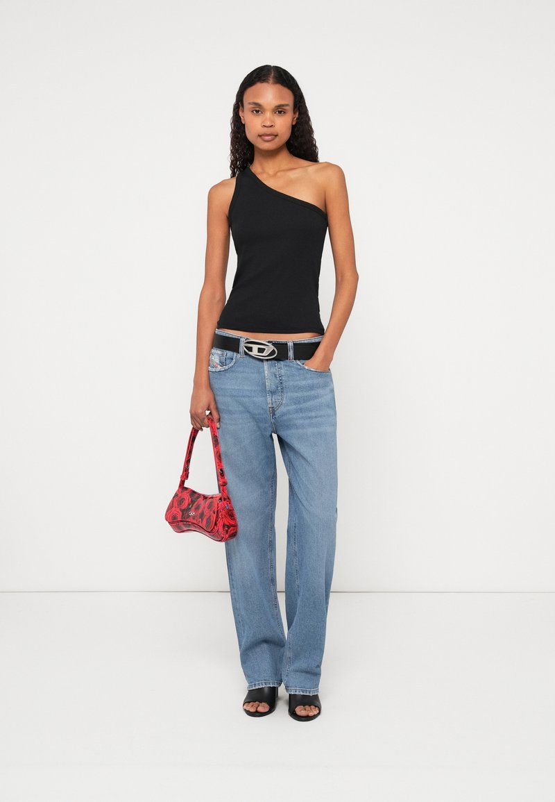 Schwarzes Ein-Schulter-Oberteil, Jeans, schwarze Sandalen mit offenem Zehenbereich und eine rote Mini-Handtasche mit Muster und Griff. Ein silberner Gürtel mit Schnalle betont die Taille.