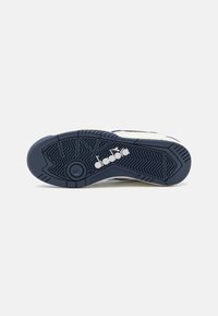 Sole di scarpa sportiva in gomma blu navy con un motivo testurizzato. Presenta un logo bianco e un accento circolare al centro. Design del tallone arrotondato.
