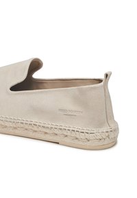 Scarpa slip-on in suede beige con una forma arrotondata e un taglio rotondo. Presenta una suola in juta intrecciata e un logo in rilievo sul lato. Texture liscia con un design minimalista.
