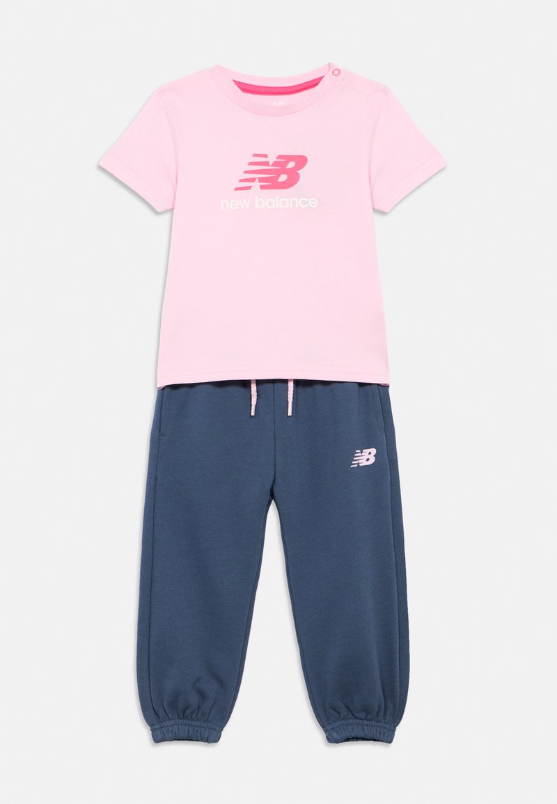 Pink short-sleeve New Balance t-shirt with logo paired with navy blue drawstring jogger pants featuring elastic cuffs and logo.