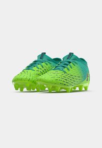 Green and turquoise soccer cleats with a textured upper, featuring a dynamic pattern, lace-up design, and six protruding studs for traction.
