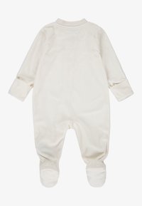 Krém színű, hosszú ujjú bébi overál, lábfejvédős kialakítással és diszkrét Nike logó mintával. Puha, sima anyag.