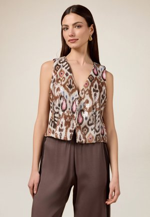 Bruin en wit gestreepte vest met roze accenten, met een V-hals ontwerp en mouwloze snit, gedragen met bruine broek.