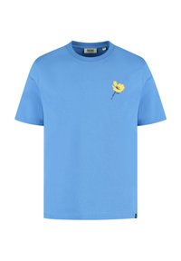 Camiseta de algodón de manga corta y cuello redondo en color azul claro. Presenta un diseño de flor amarilla en el lado izquierdo del pecho. Etiqueta visible en el cuello.