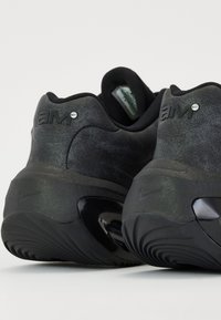 Chaussures de sport noires avec une finition mate texturée. Présentent un talon moulé, un logo Nike sur le côté et des détails brillants autour de la semelle.
