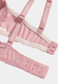 Sujetador rosa claro con tirantes ajustables, borde de encaje y cierre de gancho y ojal. Fabricado con tela suave, presenta bordes con forma de onda y hardware resistente.