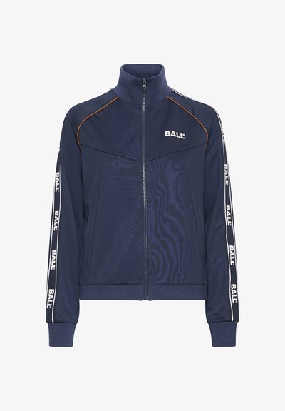 Granatowa kurtka zapinana na zamek z wysokim kołnierzem, bocznymi kieszeniami i kontrastującymi brązowymi lamówkami; posiada białe logo "BALL" wzdłuż rękawów.