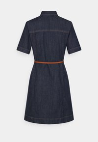 Robe en denim bleu foncé à manches courtes avec une fine ceinture marron et des coutures apparentes, vue de dos sur fond blanc.