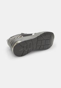 Scarpa atletica grigia con suola in gomma testurizzata, parte superiore in tessuto con un accento a stampa zebra e un dettaglio con cerniera argentata.