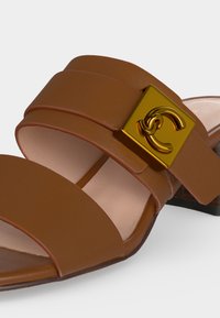 Καφέ δερμάτινο σανδάλι με δύο φαρδιές λουρίδες και χρυσή τετράγωνη αγκράφα με διπλό λογότυπο C.