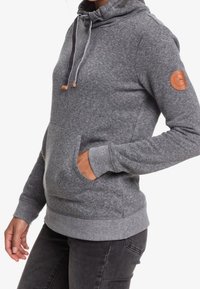 Felpa grigia con cappuccio realizzata in un tessuto morbido, dotata di una tasca frontale, cordino regolabile e una patch con logo sulla manica sinistra.