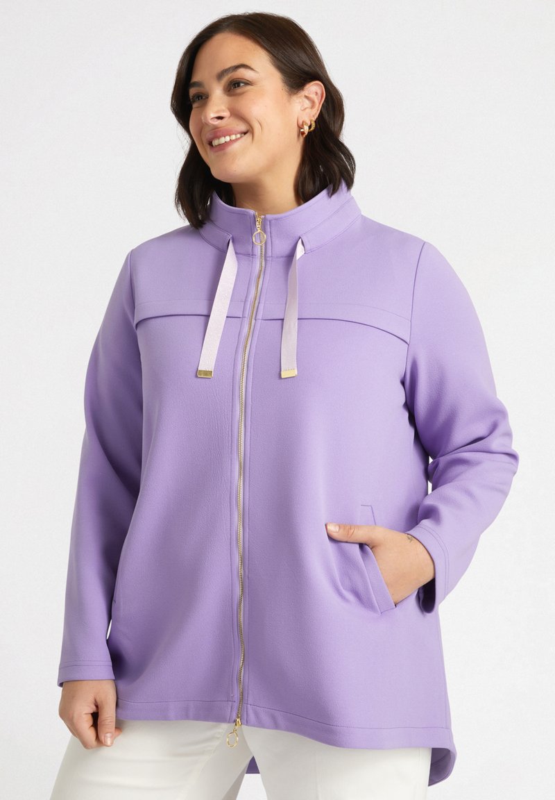 Giacca zip-up di un leggero colore viola con colletto alto, zip dorata e due tasche laterali. Materiale morbido con una texture liscia e una vestibilità comoda.