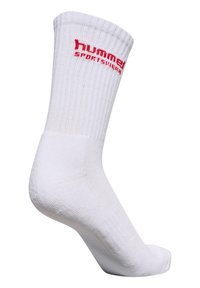 Biała skarpetka sportowa z żeberkową fakturą, wzmocnionym piętą i czerwoną marką "hummel" z boku. Standardowa długość, materiał mieszanki bawełny.