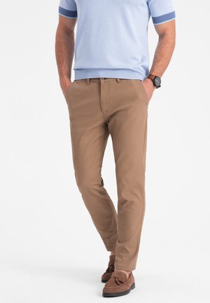 Tan chino's met een slim fit, voorzien van achterzakken, een gladde textuur en een lichtgewicht ontwerp, gecombineerd met bruine suede instappers.