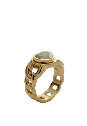 Bague en chaîne dorée ornée d'une pierre précieuse verte en forme de cœur, photographiée sur un fond blanc.